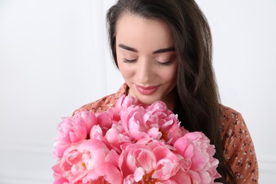 Photo of Beautiful young woman with bouquet of pink peonies on white background