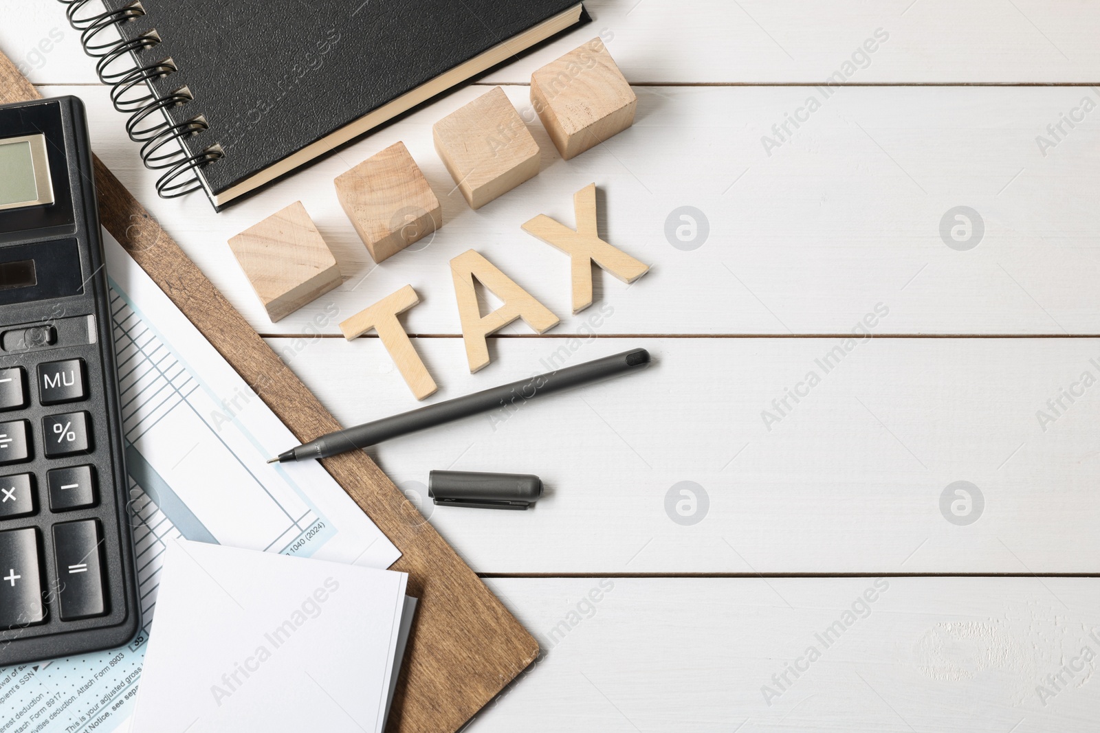 Photo of Word Tax made of letters, cubes, calculator, notebook and documents on white wooden table, flat lay. Space for text