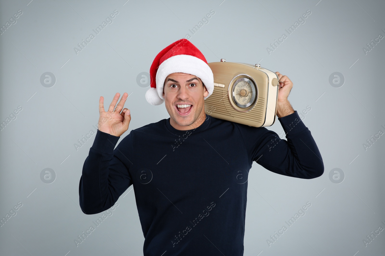 Photo of Emotional man with vintage radio on light grey background. Christmas music