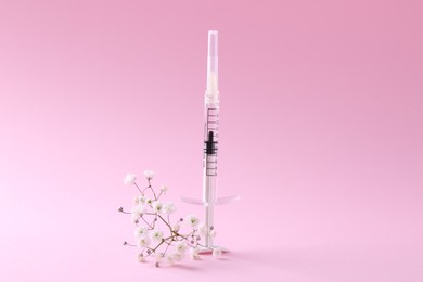 Photo of Cosmetology. Medical syringe and gypsophila on pink background