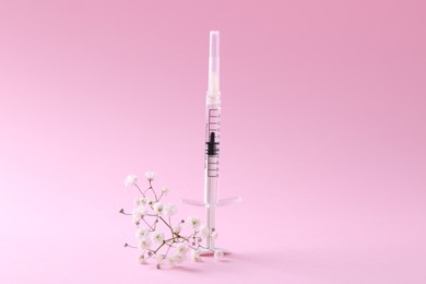 Cosmetology. Medical syringe and gypsophila on pink background