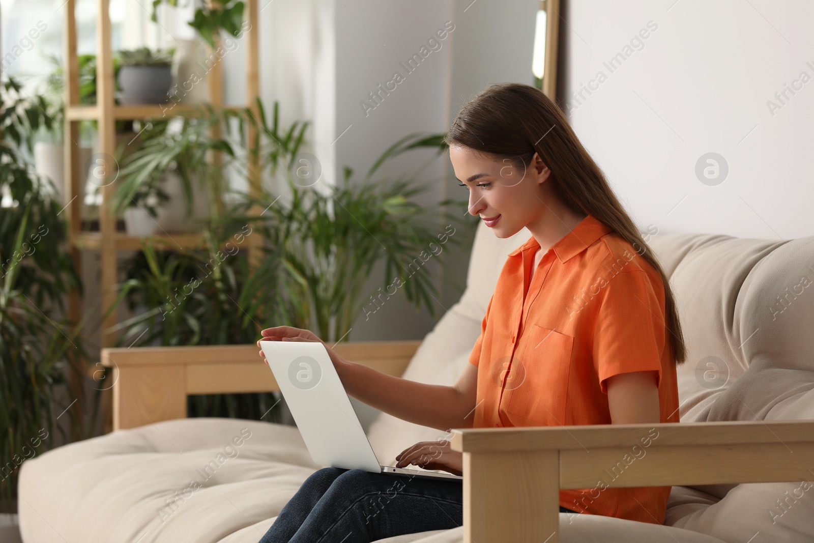 Photo of Happy young woman with laptop on sofa at home