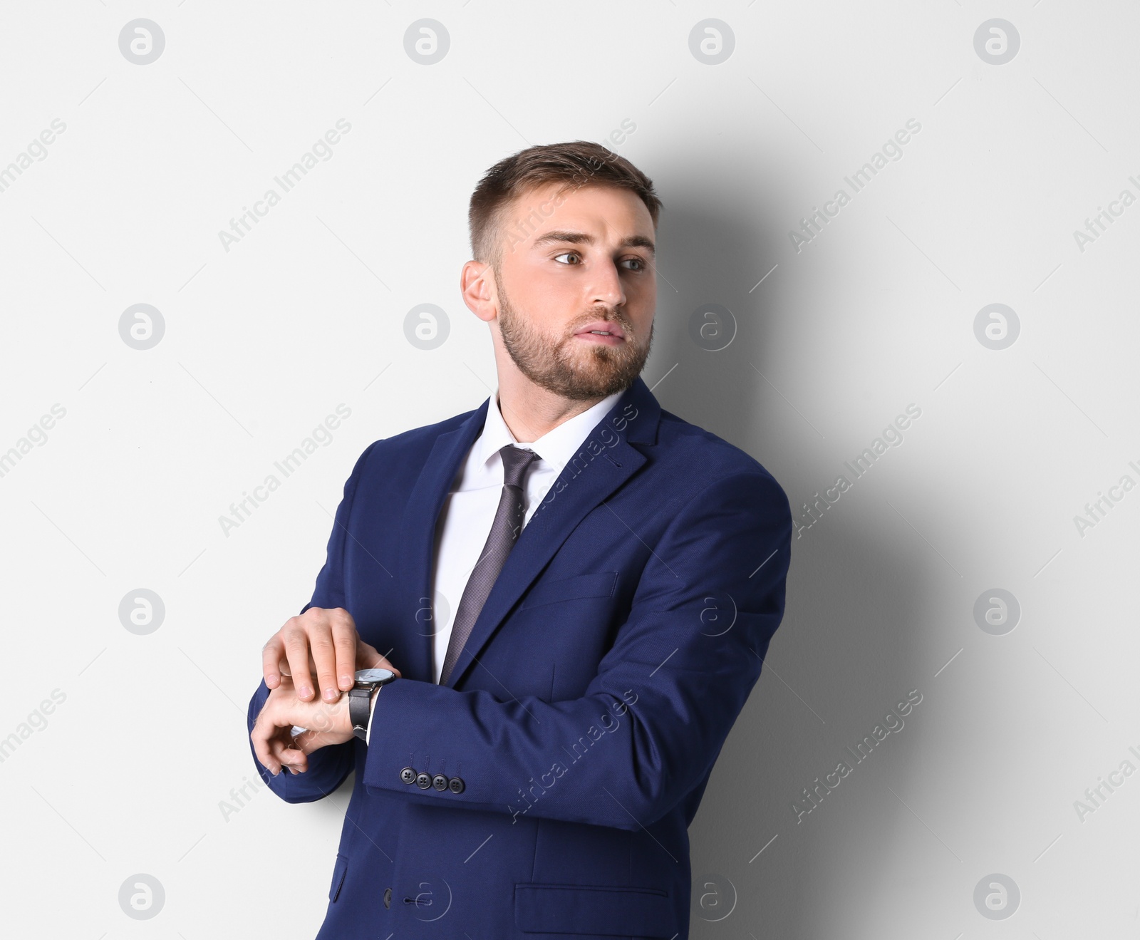 Photo of Portrait of man in office suit checking time on white background