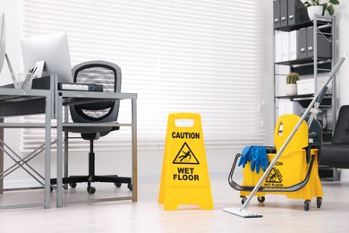 Cleaning service. Mop, wet floor sign and bucket with supplies in office