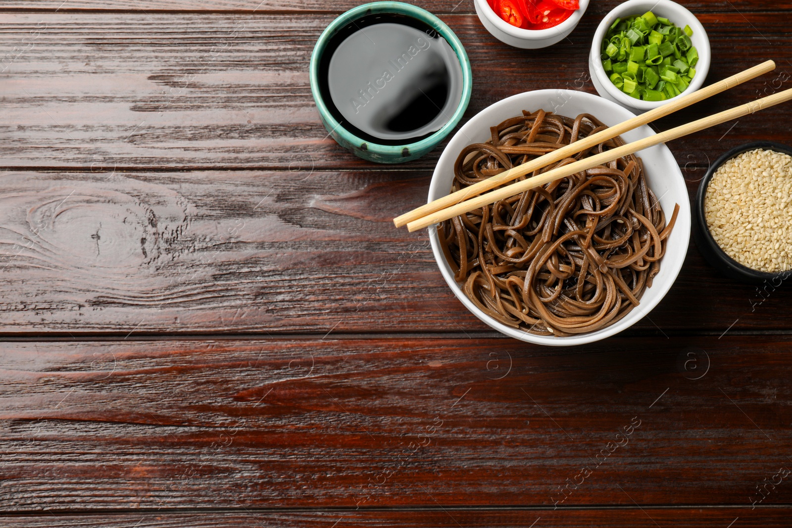 Photo of Tasty buckwheat noodles (soba) served on wooden table, flat lay. Space for text