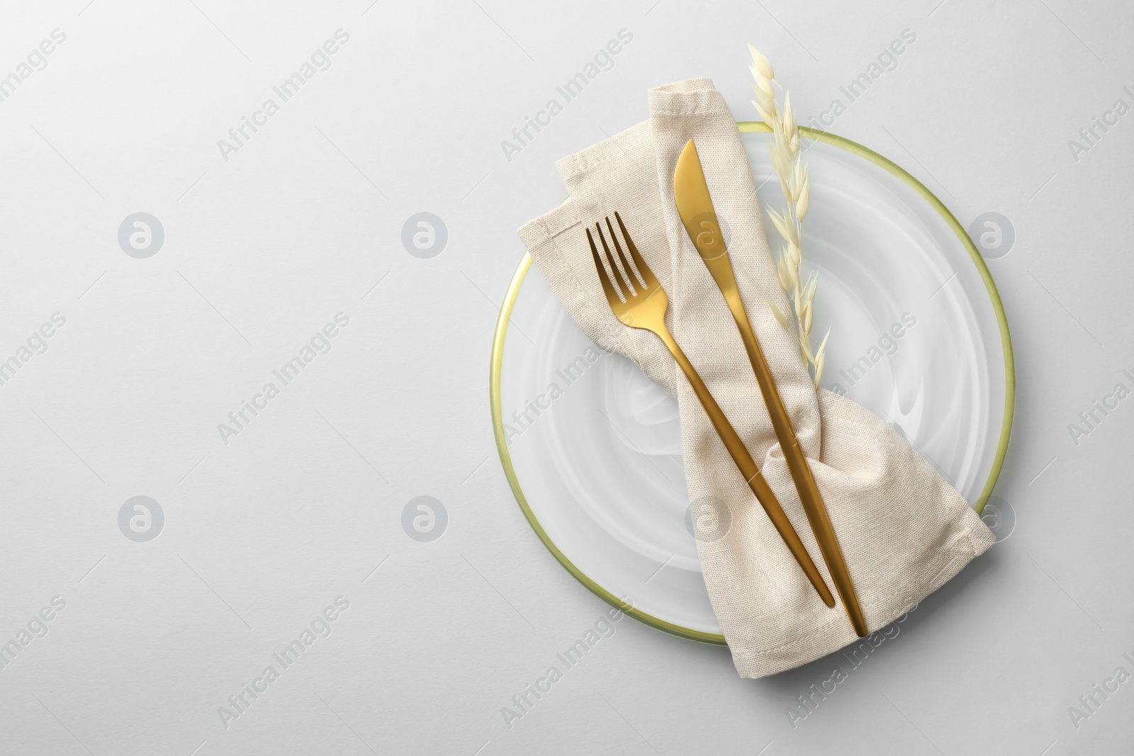 Photo of Stylish setting with cutlery, napkin, dry branch and plate on light grey table, top view. Space for text