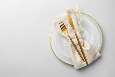 Photo of Stylish setting with cutlery, napkin, dry branch and plate on light grey table, top view. Space for text