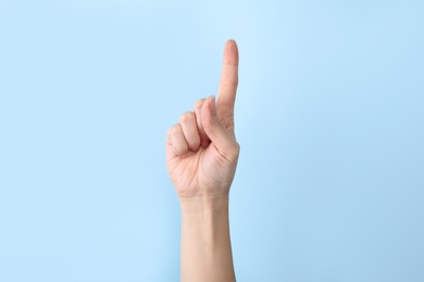 Photo of Woman showing number one on color background, closeup. Sign language
