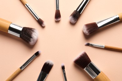 Photo of Frame of makeup brushes on beige background, flat lay. Space for text