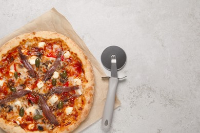 Photo of Tasty pizza with anchovies and cutter on grey table, top view. Space for text