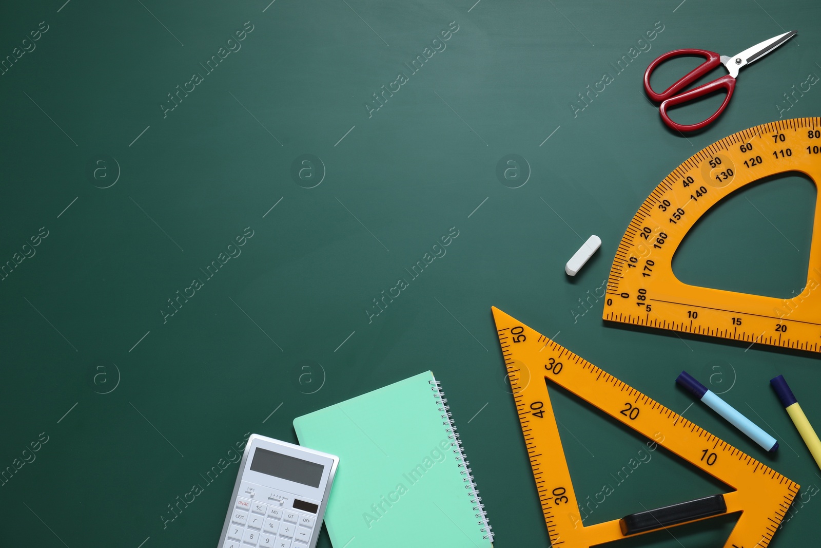 Photo of Flat lay composition with protractor, triangle and stationery on green chalkboard. Space for text