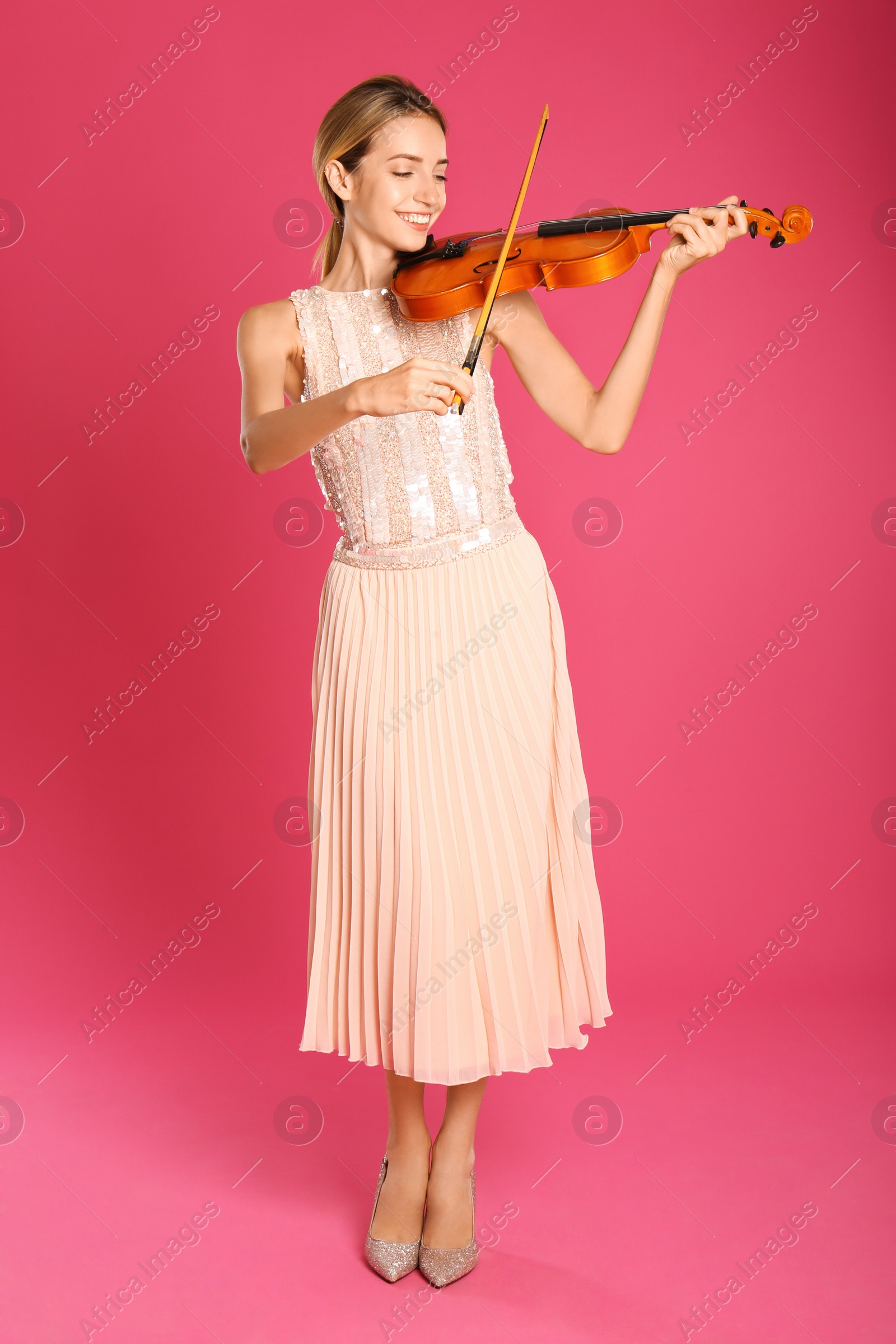 Photo of Beautiful woman playing violin on pink background