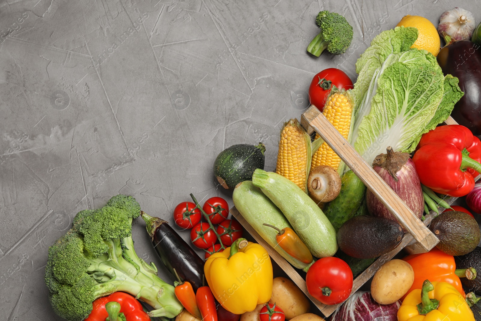 Photo of Many different ripe vegetables and basket on grey background, flat lay. Space for text