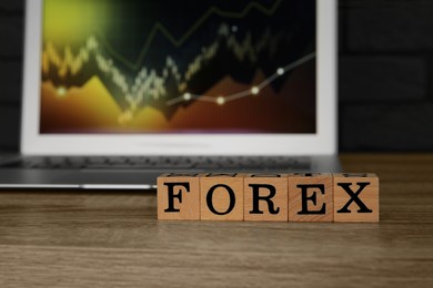 Photo of Word Forex made with cubes and laptop on wooden table