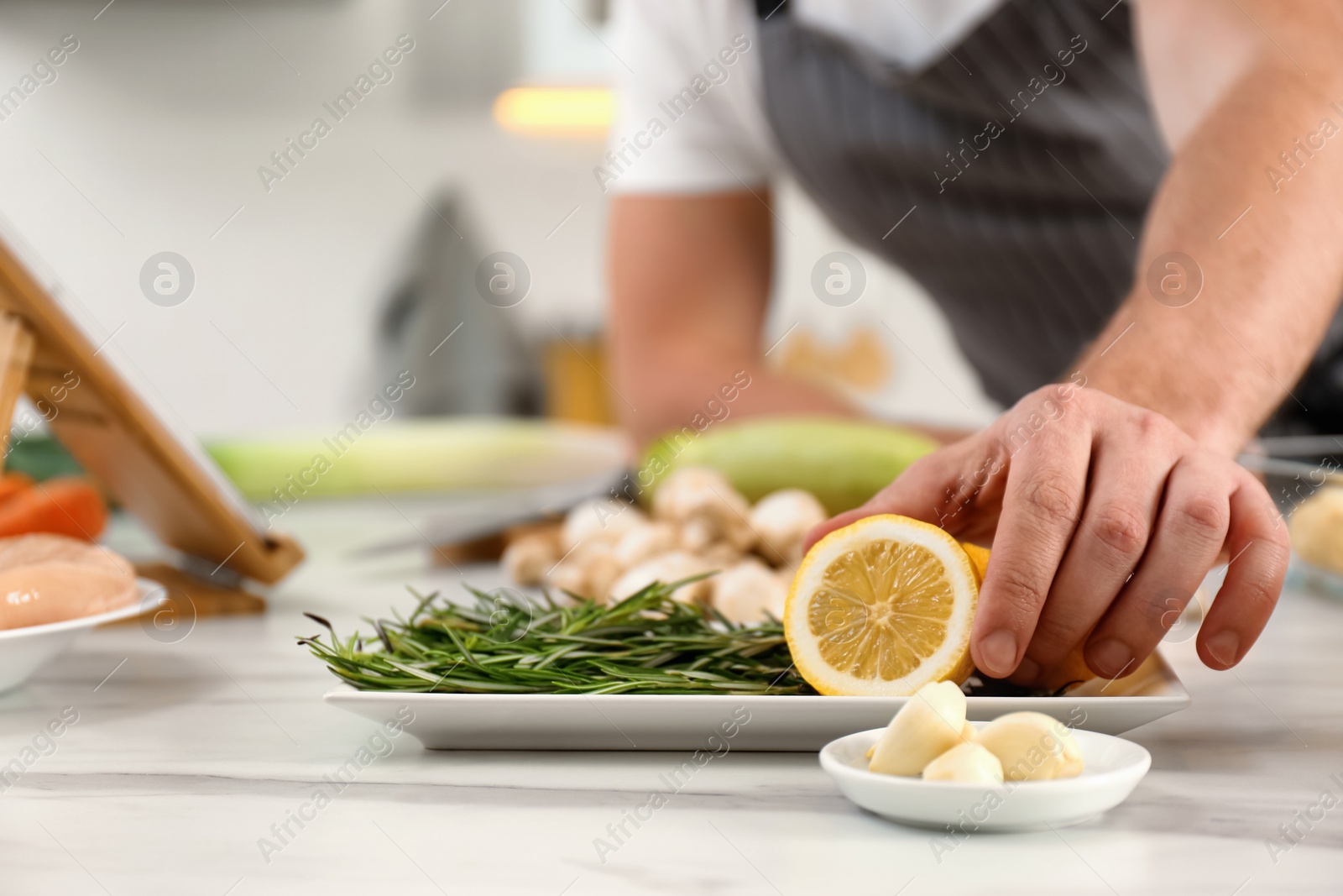 Photo of Man making dinner while watching online cooking course via tablet kitchen, closeup