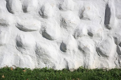 White stone wall of building near green grass outdoors. Exterior design
