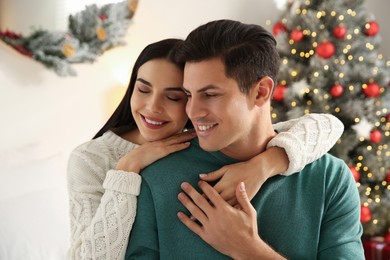 Happy couple near decorated Christmas tree indoors