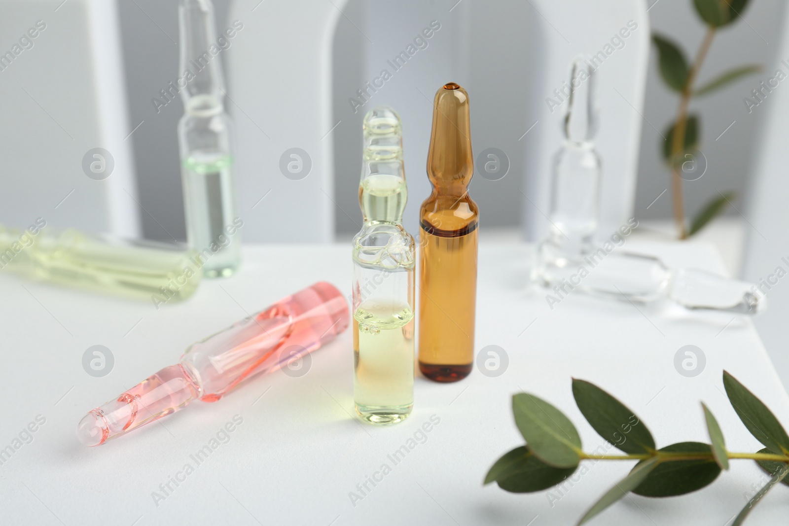 Photo of Stylish presentation of different skincare ampoules on white background, closeup