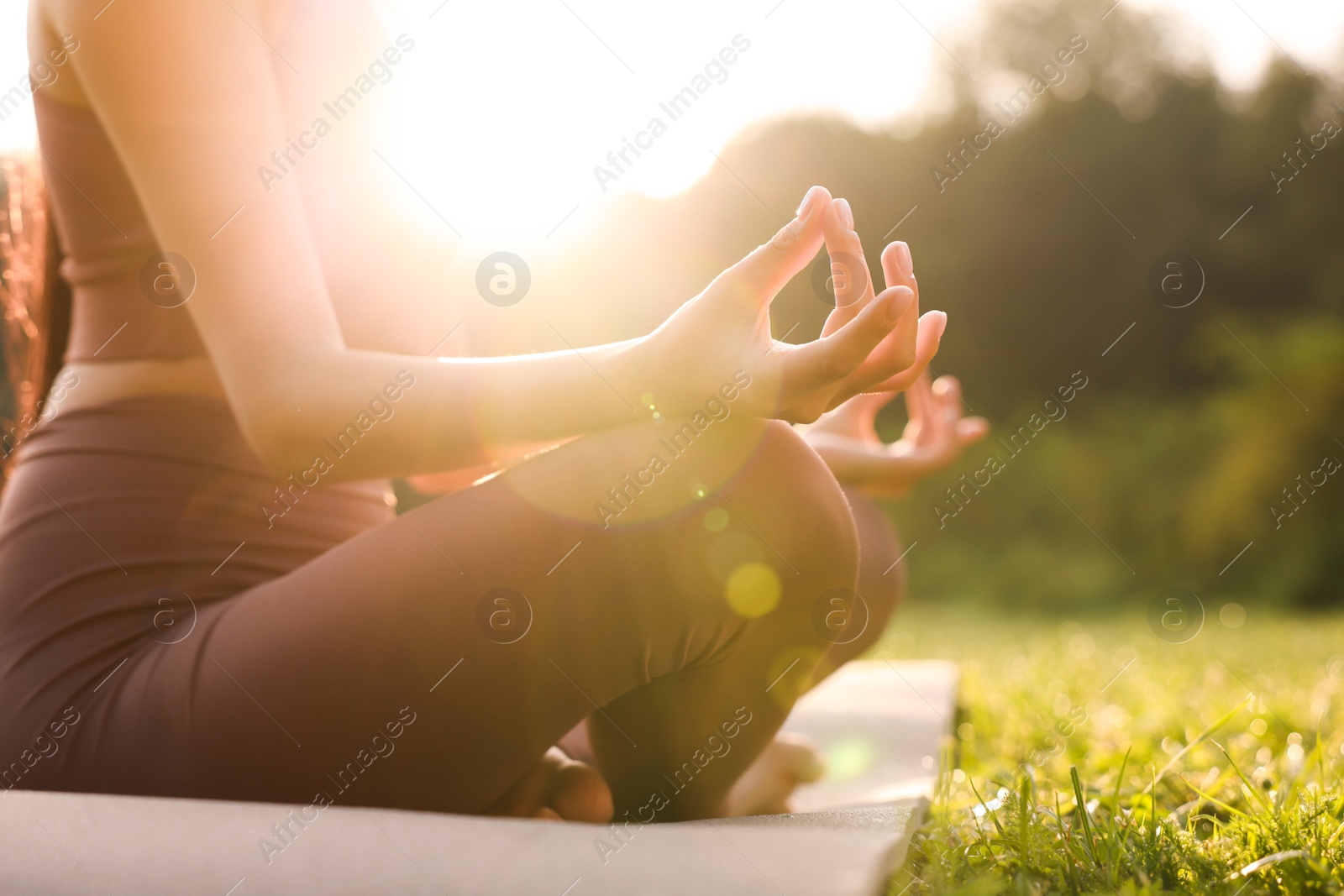 Photo of Woman practicing Padmasana on yoga mat outdoors, closeup. Lotus pose