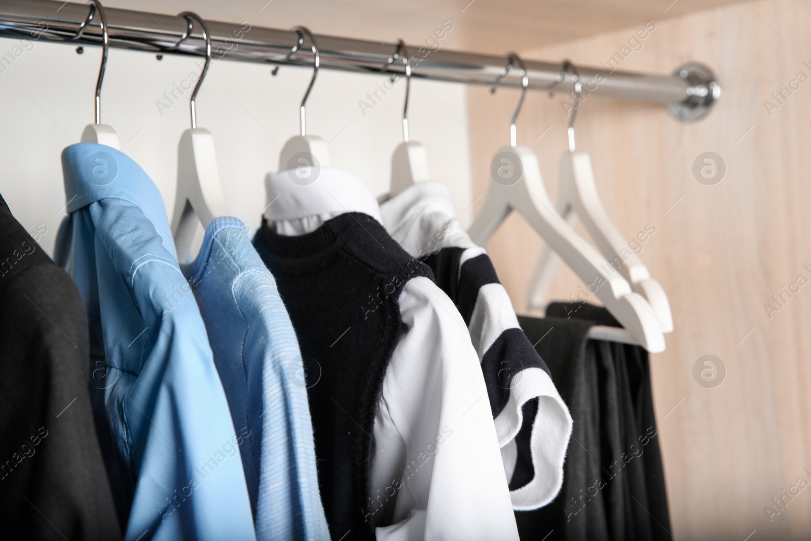 Photo of Stylish boy's clothes hanging in wardrobe, closeup