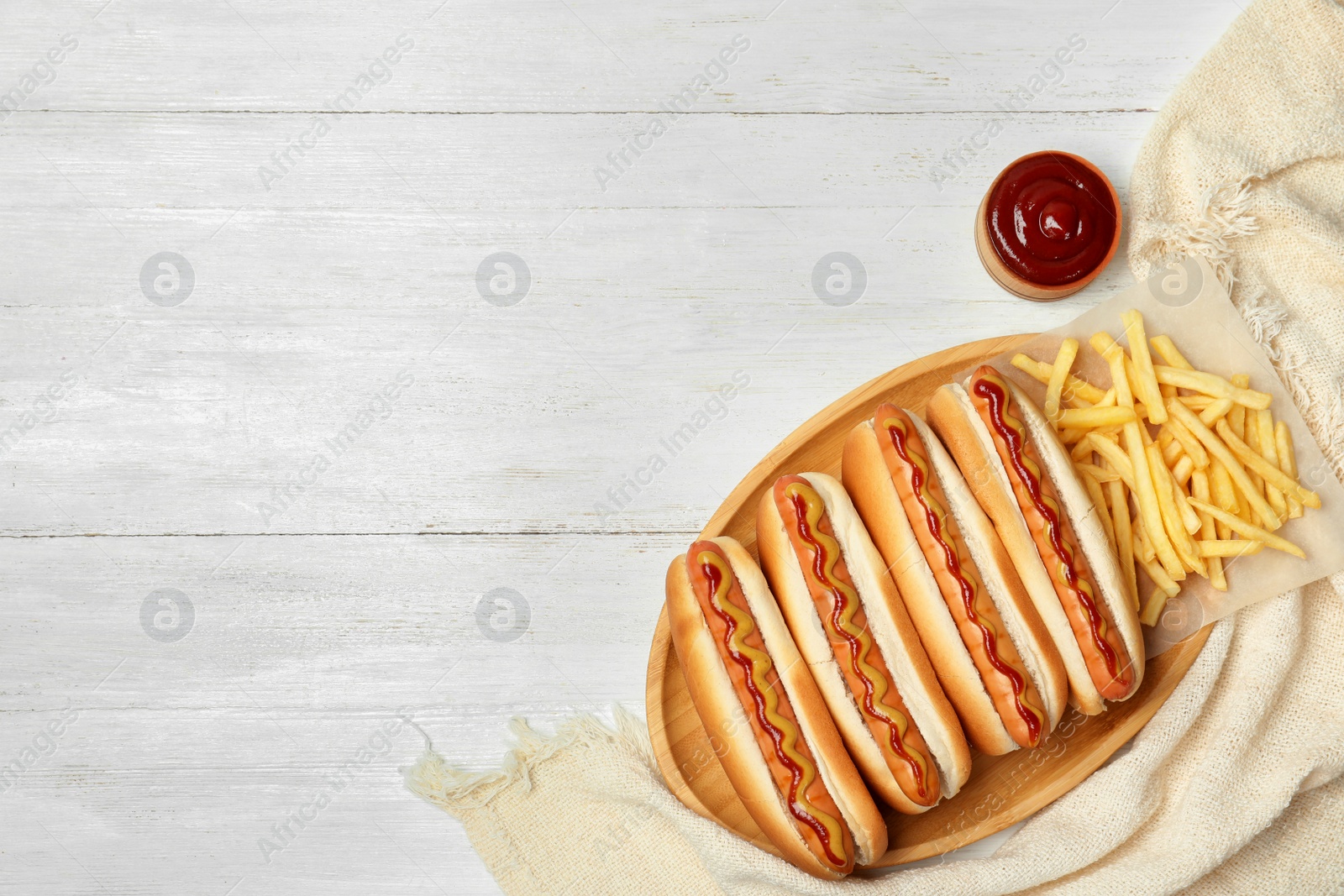 Photo of Composition with hot dogs, french fries and sauce on wooden table, top view. Space for text