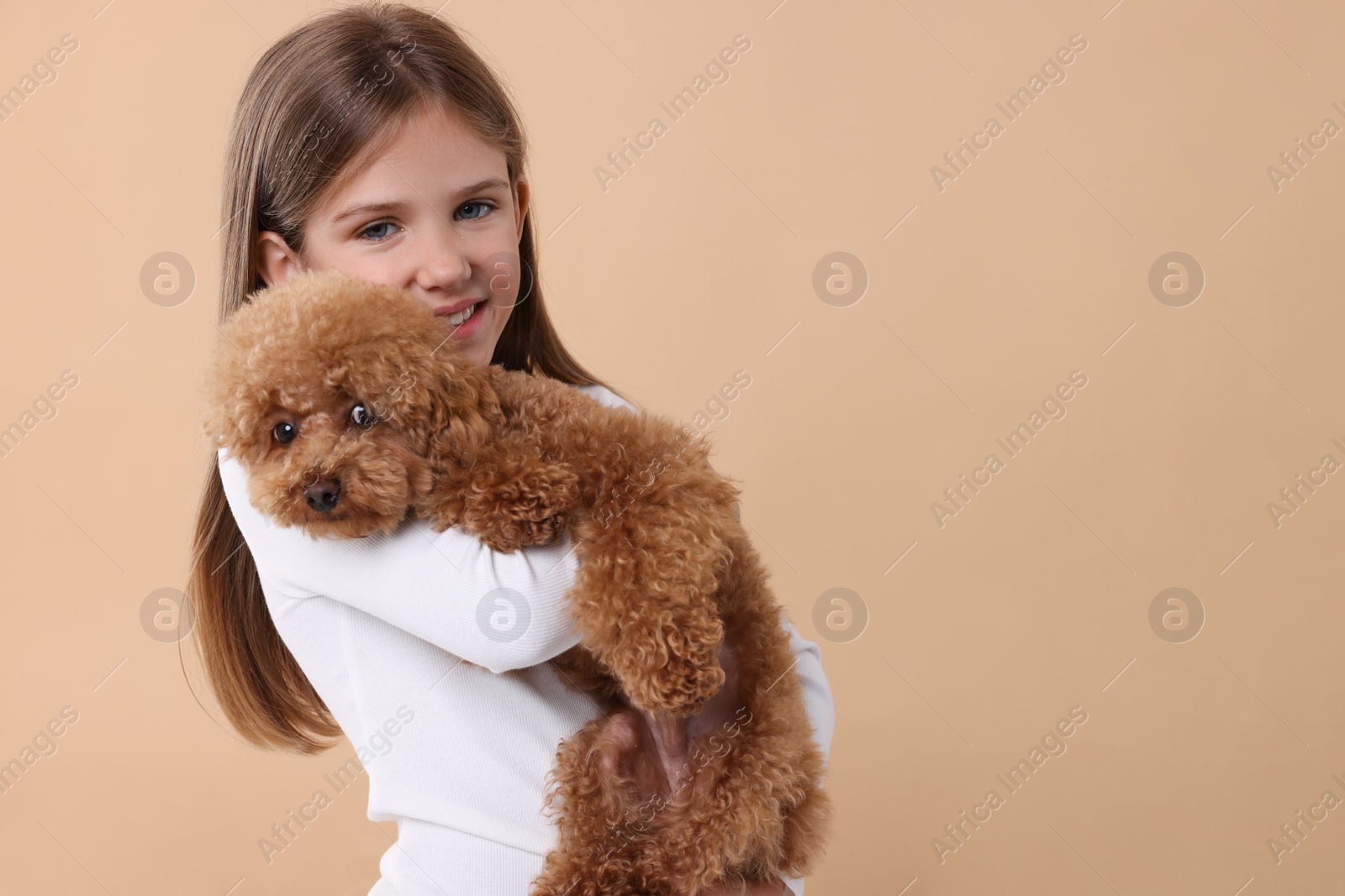 Photo of Little child with cute puppy on beige background, space for text. Lovely pet