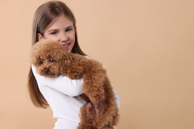 Photo of Little child with cute puppy on beige background, space for text. Lovely pet