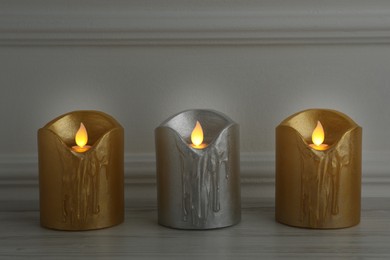 Photo of Glowing decorative LED candles on wooden table