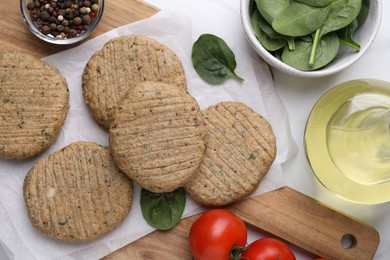 Photo of Raw vegan cutlets and different products on white table, flat lay