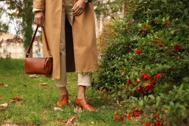 Photo of Stylish woman with trendy leather bag in autumn park, closeup