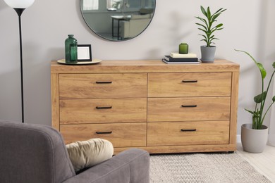 Cozy room interior with chest of drawers, mirror, armchair and decor elements