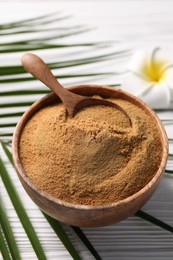 Photo of Coconut sugar and spoon in bowl on white wooden table, closeup