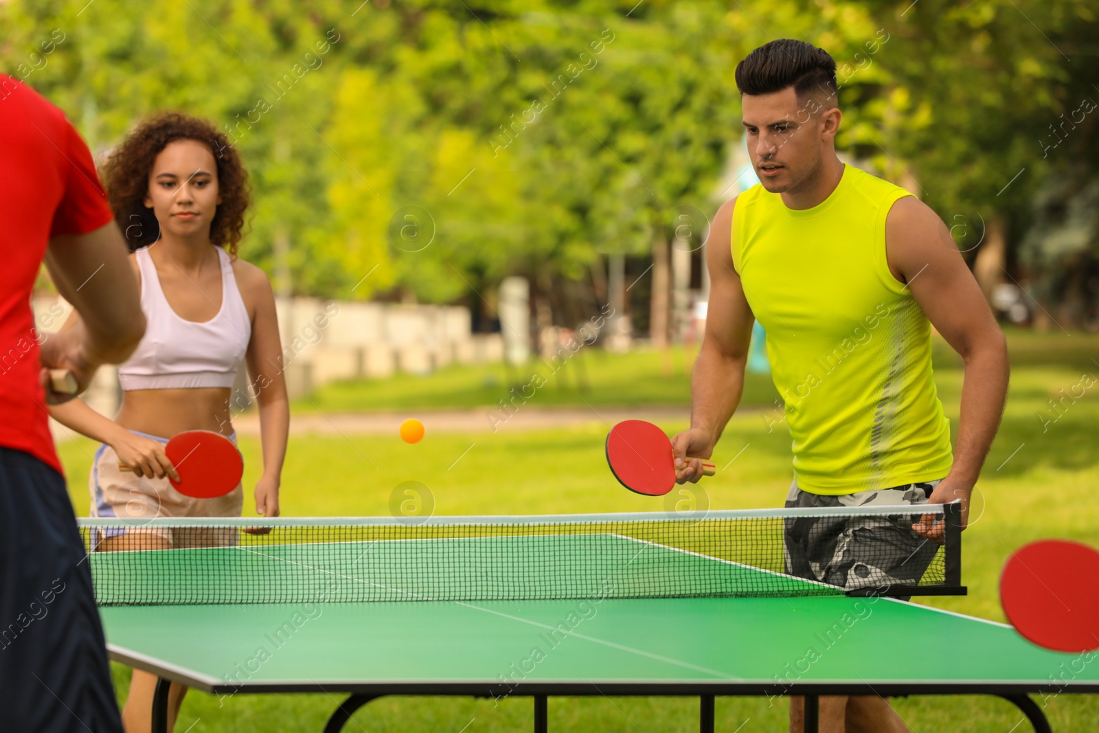 Photo of Friends playing ping pong outdoors on summer day