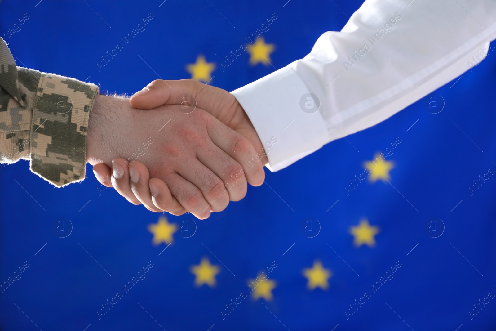 Photo of Soldier and businessman shaking hands against flag of European Union, closeup