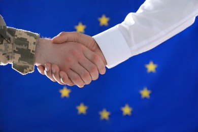 Soldier and businessman shaking hands against flag of European Union, closeup
