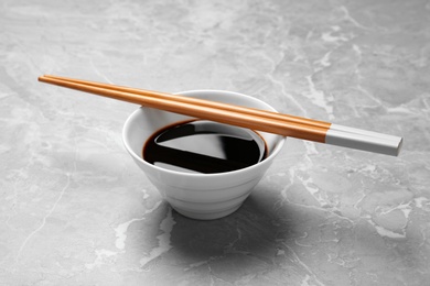 Bowl of soy sauce with chopsticks on marble background