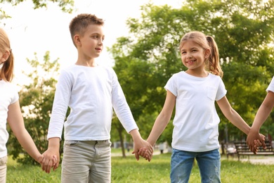 Group of children holding hands together in park. Volunteer project