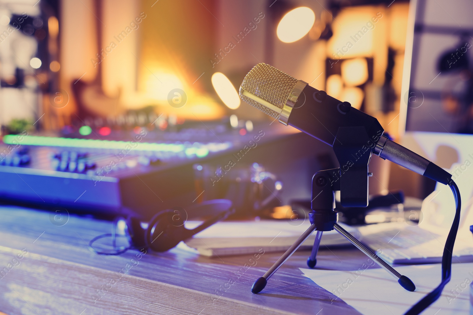 Photo of Microphone near professional mixing console on table in radio studio