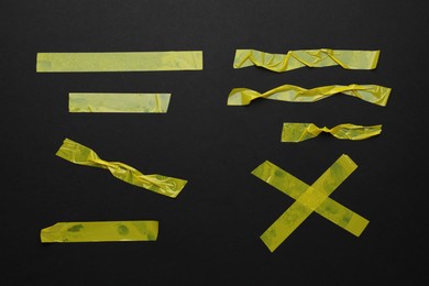 Many pieces of yellow adhesive tape on black background, flat lay