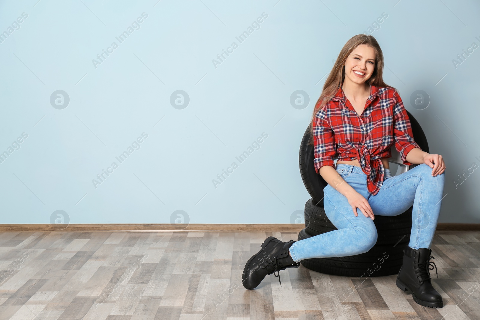 Photo of Young woman in seductive outfit with car tires on grey wall background