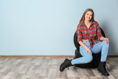 Young woman in seductive outfit with car tires on grey wall background