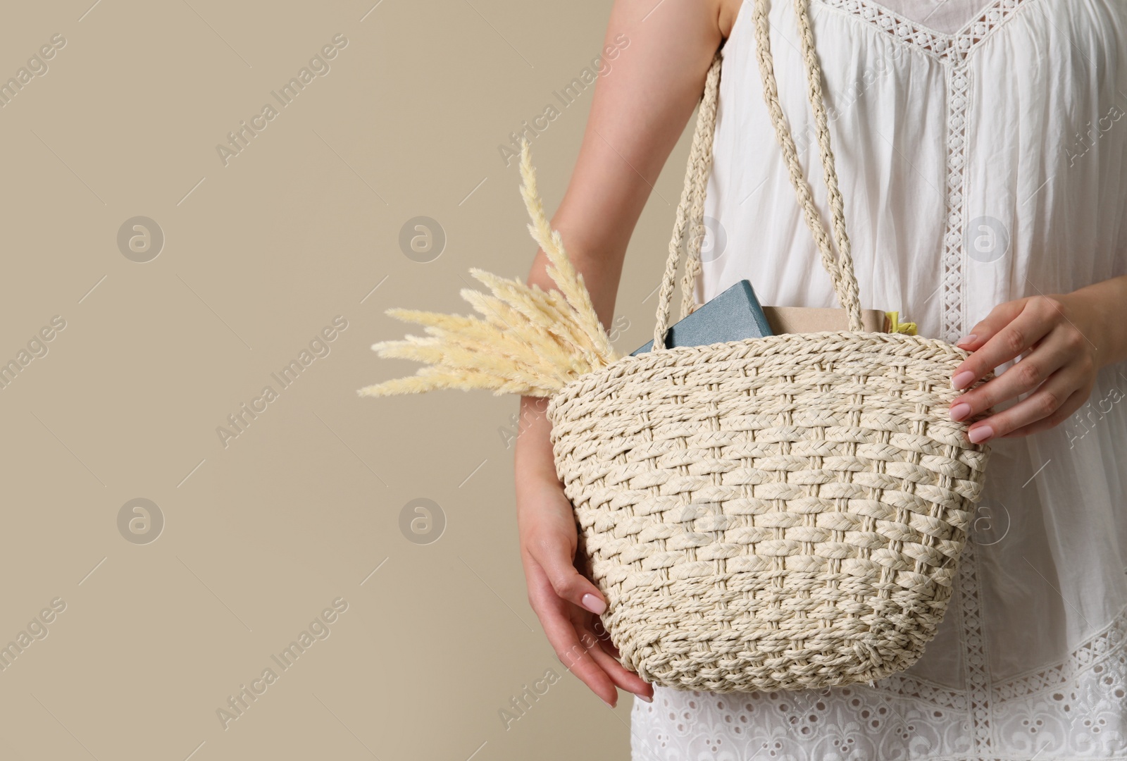 Photo of Woman holding beach bag on beige background, closeup. Space for text