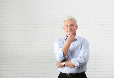 Photo of Portrait of handsome mature man near brick wall. Space for text