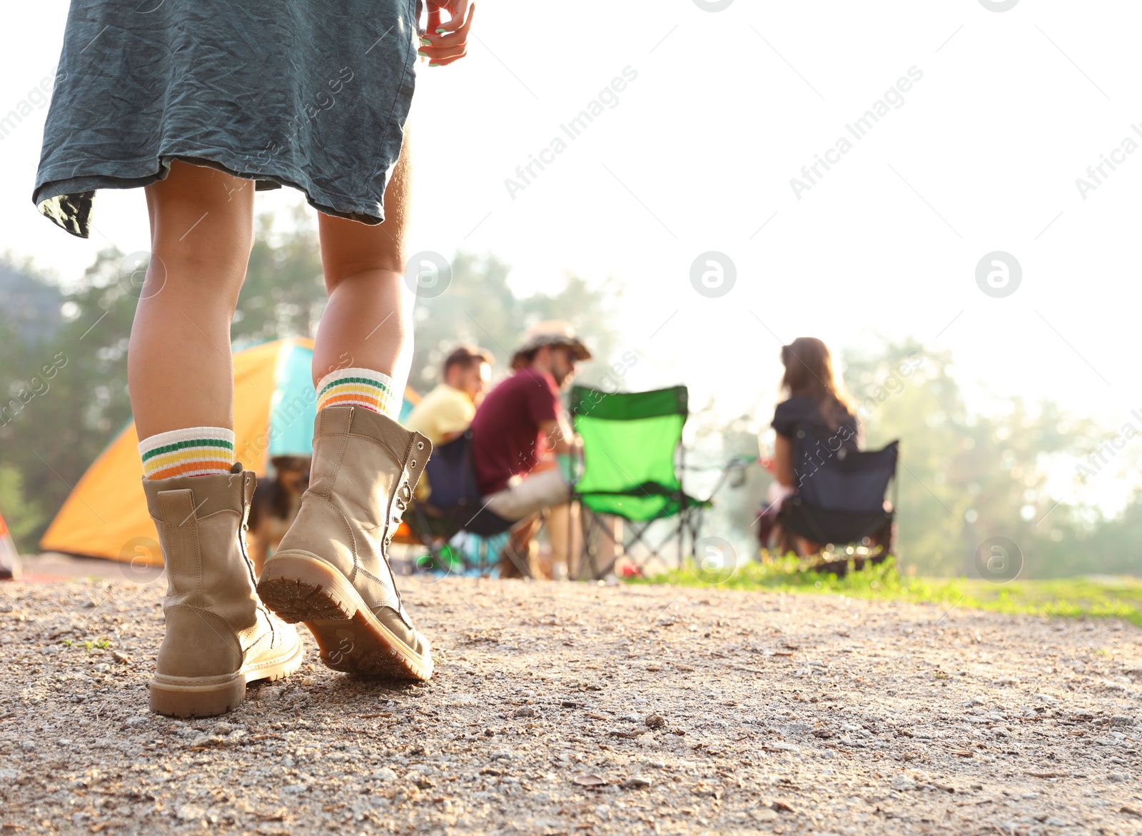 Photo of Young woman near camping tent in wilderness, focus on legs
