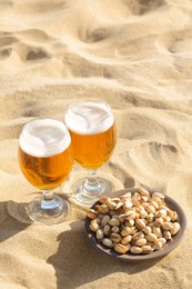 Glasses of cold beer and pistachios on sandy beach