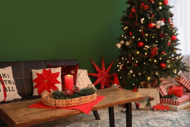 Photo of Wicker tray with red candle and fir branches on wooden table indoors, space for text. Christmas decor