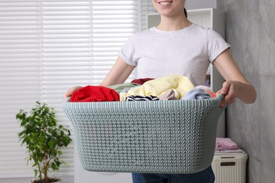 Photo of Woman with basket full of laundry in bathroom, closeup