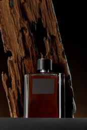 Photo of Luxury men`s perfume in bottle on grey table against dark background