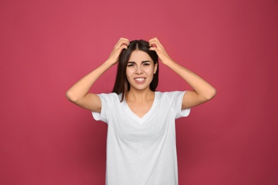 Young woman scratching head on color background. Annoying itch