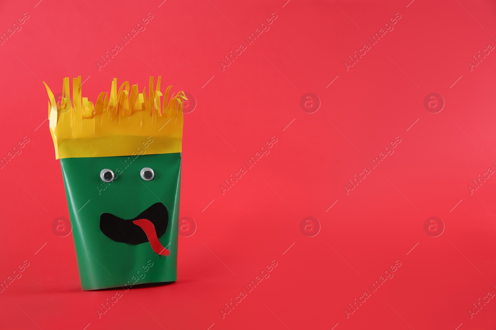 Photo of Funny green monster on red background, space for text. Halloween decoration